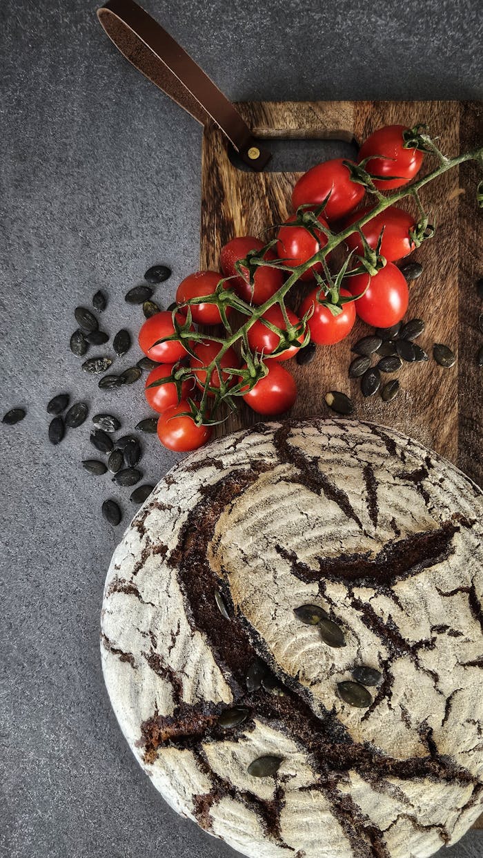 Flat lay of artisanal sourdough bread with cherry tomatoes on a wooden board.